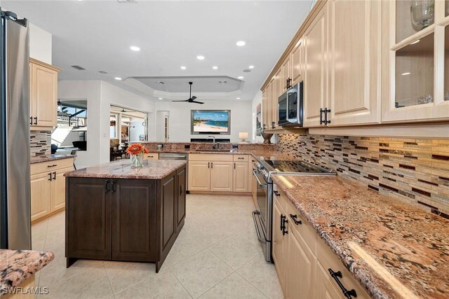 kitchen featuring appliances with stainless steel finishes, sink, decorative backsplash, light stone counters, and a raised ceiling