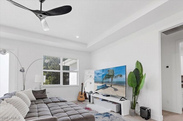 living room with a tray ceiling and ceiling fan