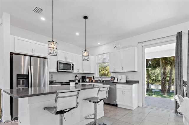 kitchen with appliances with stainless steel finishes, a center island, white cabinetry, and a kitchen breakfast bar