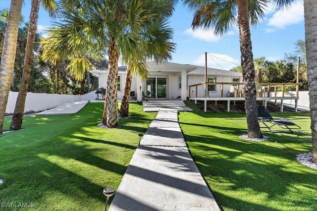 rear view of property featuring a lawn and a wooden deck