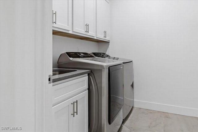 clothes washing area featuring washing machine and clothes dryer and cabinets