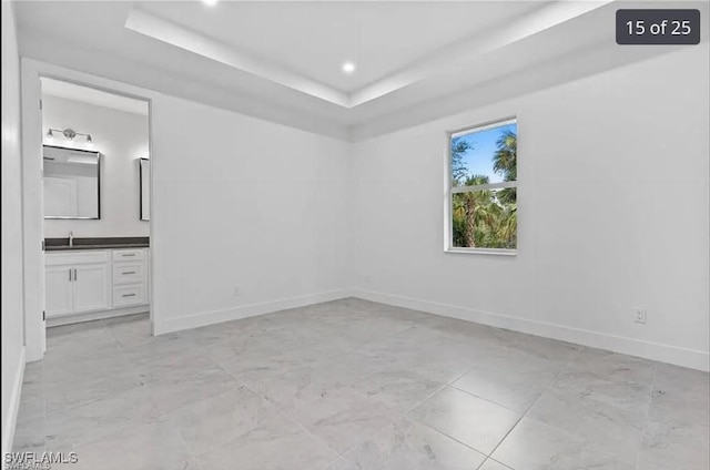 unfurnished room with a raised ceiling and sink