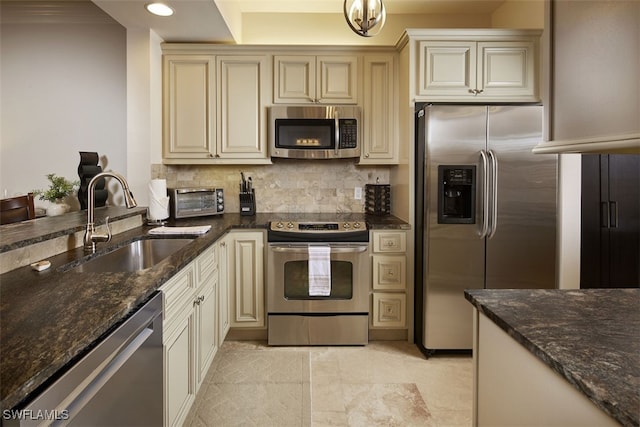 kitchen featuring dark stone counters, sink, cream cabinetry, and appliances with stainless steel finishes