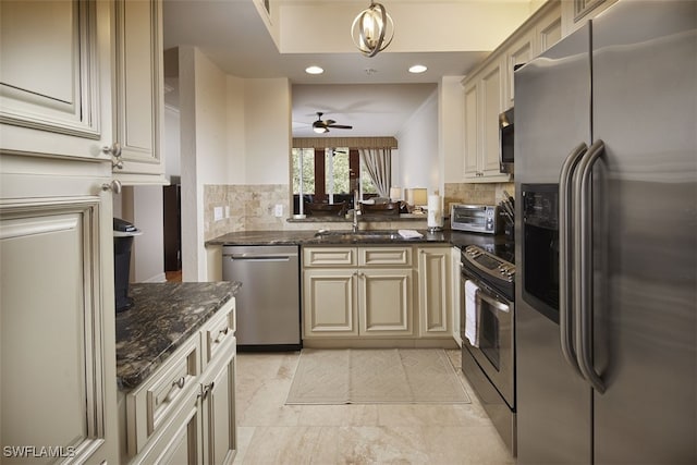 kitchen featuring cream cabinets, pendant lighting, ceiling fan with notable chandelier, and appliances with stainless steel finishes