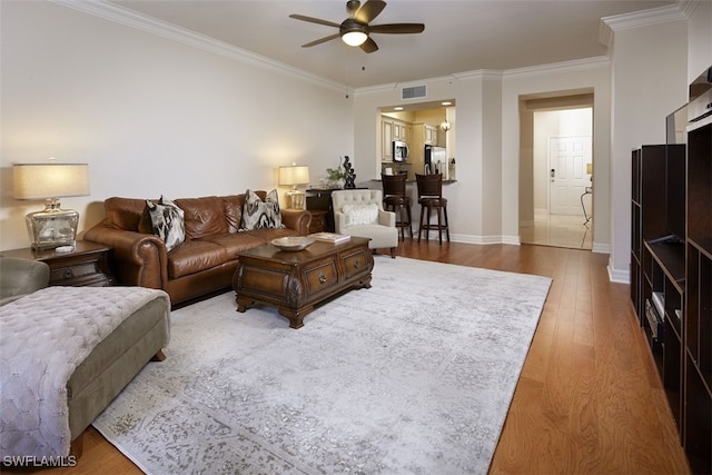 living room featuring hardwood / wood-style flooring, ceiling fan, and ornamental molding