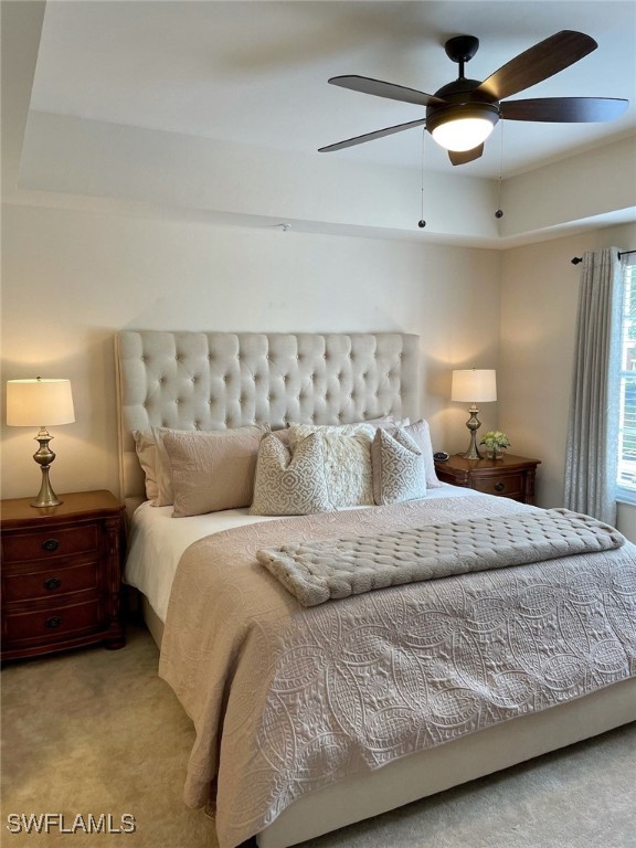 bedroom with carpet, a raised ceiling, and ceiling fan