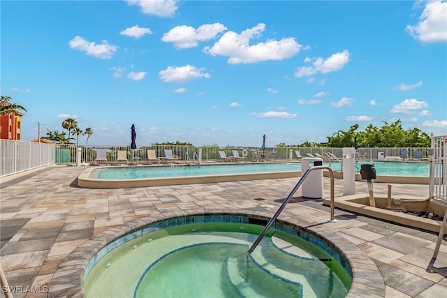 view of swimming pool featuring a patio and a hot tub