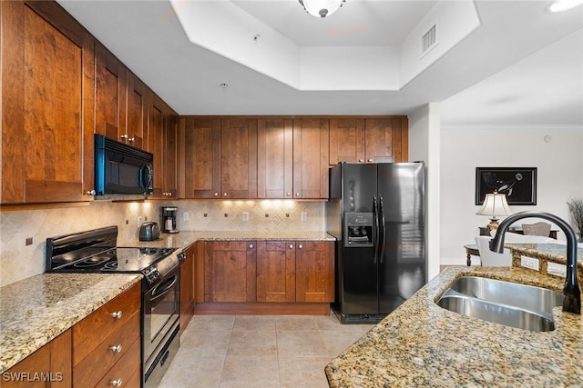 kitchen with backsplash, light stone counters, sink, and black appliances