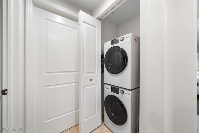 laundry area with light tile patterned floors and stacked washer and dryer