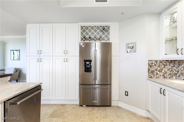 kitchen featuring backsplash, white cabinets, ornamental molding, appliances with stainless steel finishes, and light stone counters