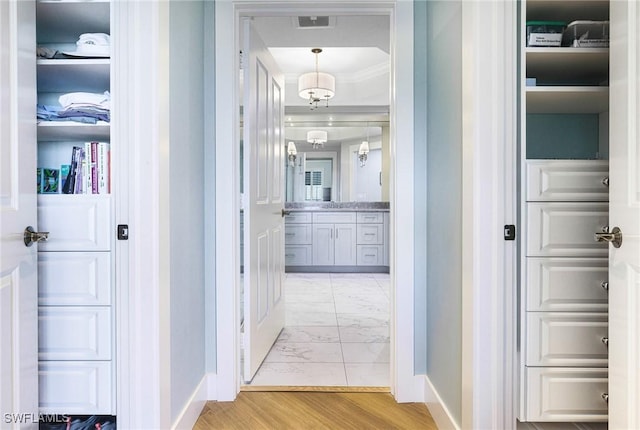 hall with light hardwood / wood-style floors and ornamental molding