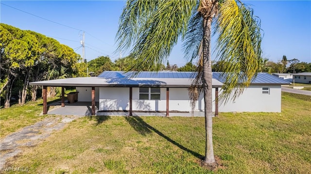 back of property with solar panels, a yard, and a carport