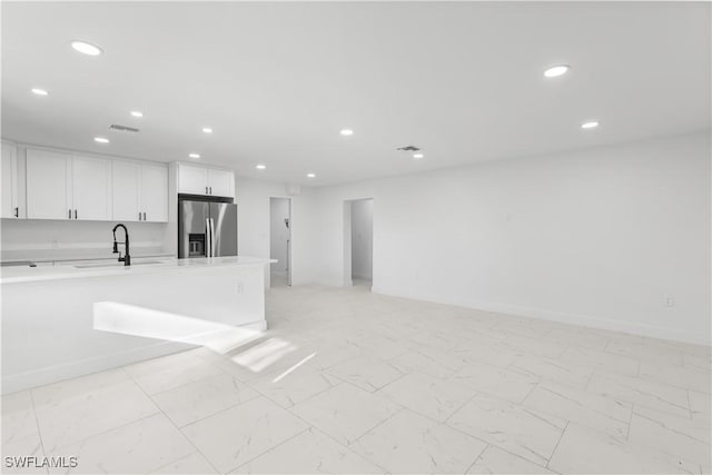 kitchen featuring sink, white cabinetry, and stainless steel refrigerator with ice dispenser