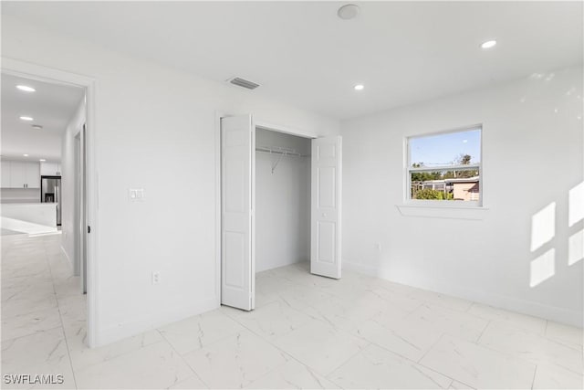 unfurnished bedroom featuring stainless steel fridge with ice dispenser and a closet