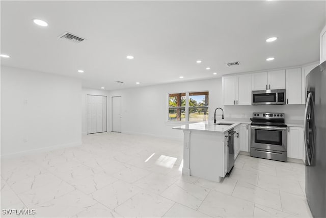 kitchen featuring white cabinets, sink, appliances with stainless steel finishes, kitchen peninsula, and a breakfast bar area