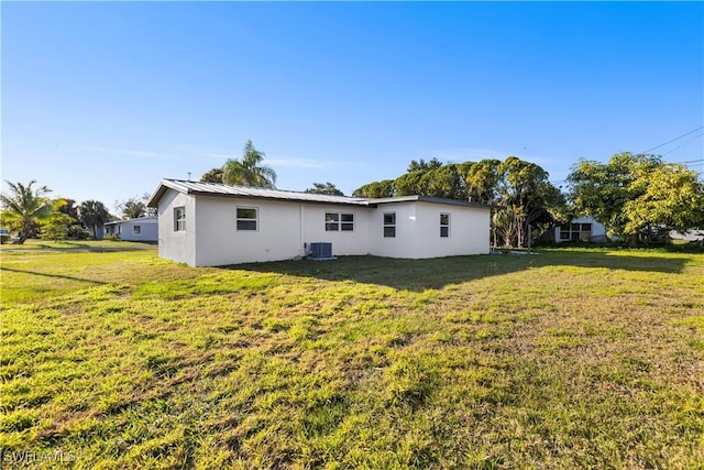 rear view of property with central AC and a lawn