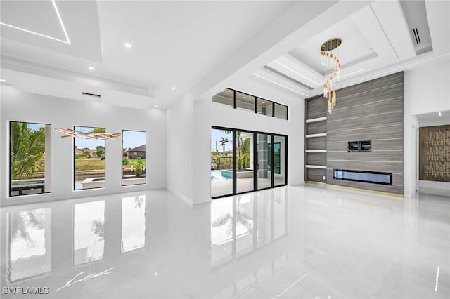 unfurnished living room with a raised ceiling, a wealth of natural light, and a fireplace