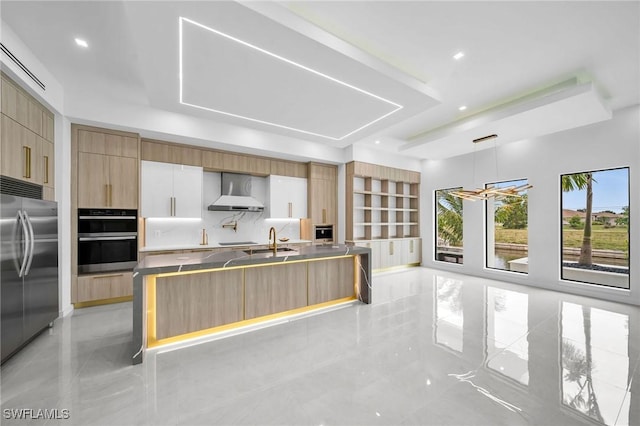 kitchen featuring wall chimney exhaust hood, stainless steel appliances, decorative light fixtures, decorative backsplash, and white cabinets