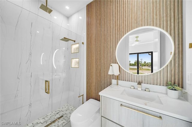 bathroom featuring vanity, ceiling fan, toilet, and a shower with shower door