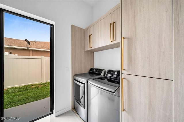 washroom with washer and dryer and cabinets