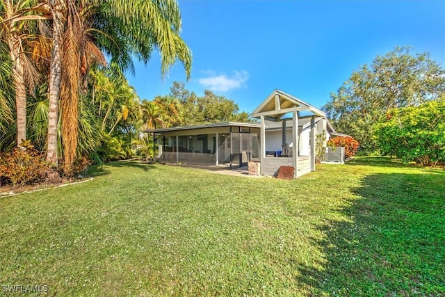 rear view of house featuring a lawn and a sunroom