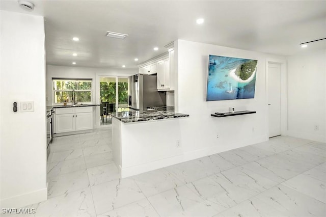 kitchen featuring kitchen peninsula, dark stone countertops, white cabinetry, and stainless steel refrigerator with ice dispenser