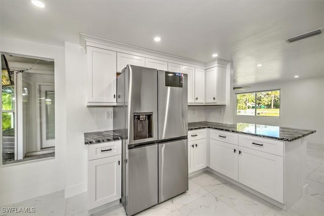 kitchen with white cabinets, dark stone countertops, kitchen peninsula, and stainless steel refrigerator with ice dispenser