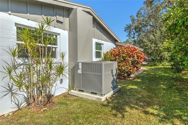 view of side of property featuring central air condition unit and a yard