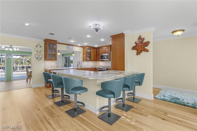 kitchen featuring brown cabinets, tasteful backsplash, a kitchen bar, and stainless steel appliances