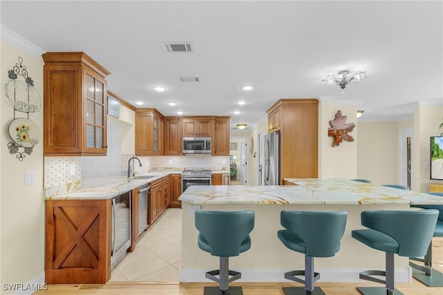 kitchen with sink, stainless steel appliances, tasteful backsplash, a kitchen bar, and ornamental molding