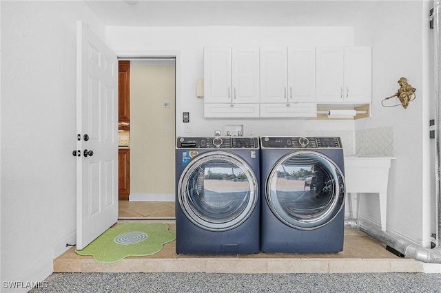 clothes washing area with washer and clothes dryer and cabinets