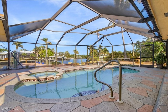 view of pool featuring glass enclosure, a water view, a patio, and an in ground hot tub