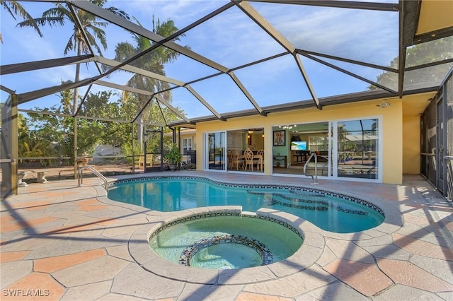 view of pool featuring glass enclosure, ceiling fan, a patio area, and an in ground hot tub