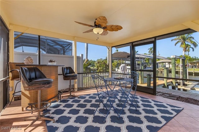 sunroom with ceiling fan, a water view, and a healthy amount of sunlight