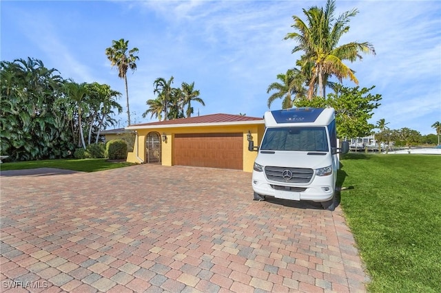 view of front of house with a garage, decorative driveway, a front lawn, and stucco siding