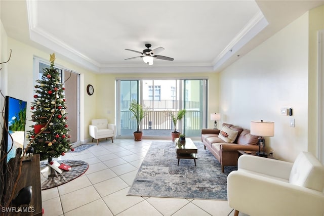 tiled living room featuring a raised ceiling, ceiling fan, and ornamental molding