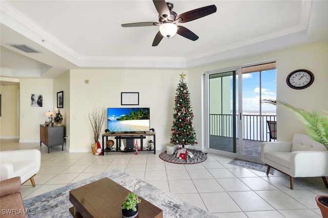 tiled living room featuring ceiling fan, ornamental molding, and a tray ceiling