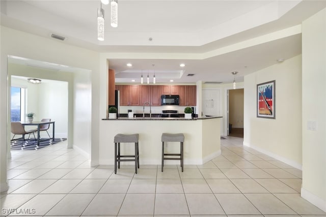 kitchen with kitchen peninsula, a tray ceiling, and hanging light fixtures