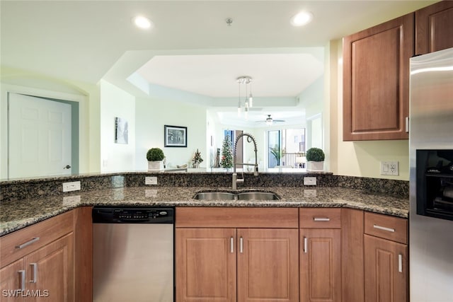 kitchen featuring stainless steel appliances, ceiling fan, dark stone counters, and sink