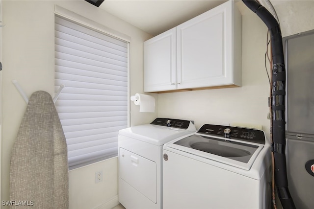 clothes washing area with cabinets, washing machine and dryer, and a healthy amount of sunlight