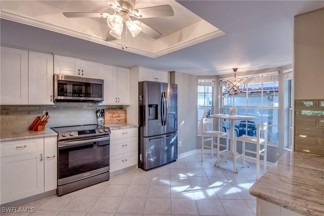 kitchen with a raised ceiling, white cabinetry, and stainless steel appliances