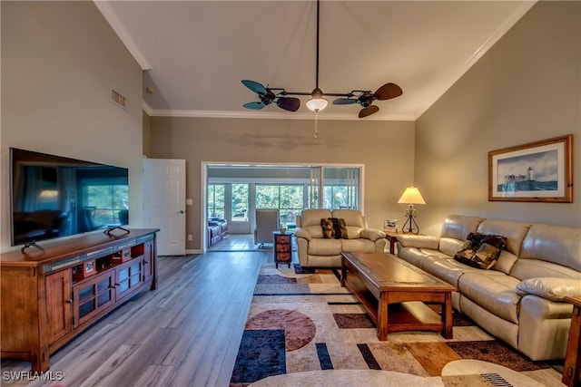 living room with a high ceiling, light wood-type flooring, ceiling fan, and ornamental molding