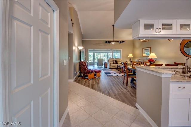 interior space featuring ceiling fan, sink, light tile patterned floors, and lofted ceiling