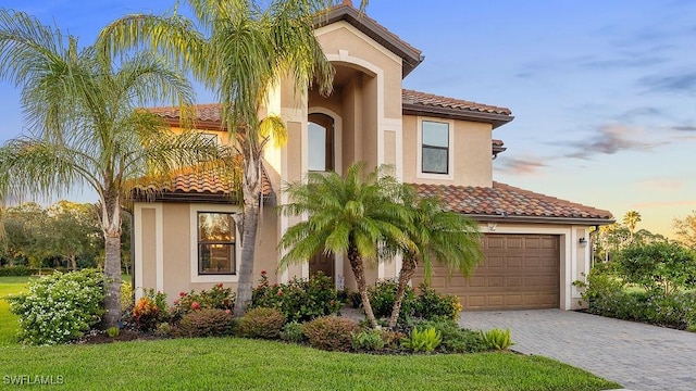 mediterranean / spanish home with a lawn and a garage