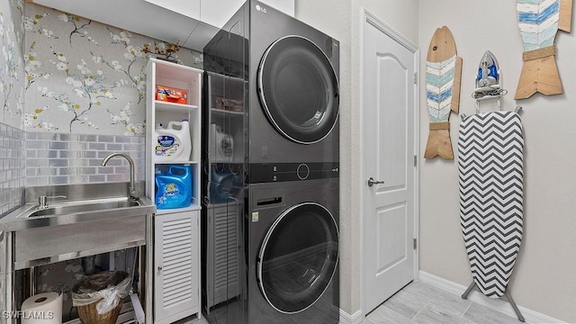 washroom with stacked washing maching and dryer and sink