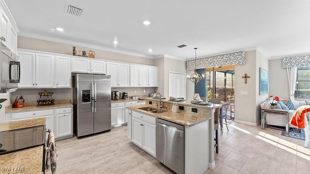 kitchen featuring hanging light fixtures, sink, appliances with stainless steel finishes, a kitchen bar, and white cabinetry