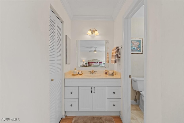 bathroom with vanity, toilet, ceiling fan, and ornamental molding