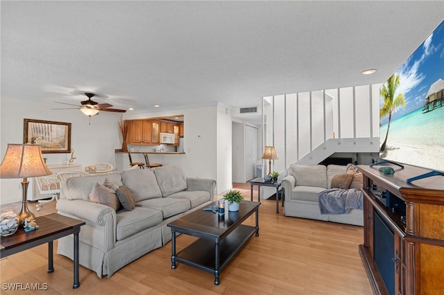 living room featuring a textured ceiling, light hardwood / wood-style floors, ceiling fan, and ornamental molding