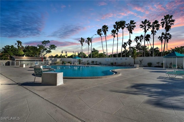 pool at dusk featuring a patio area