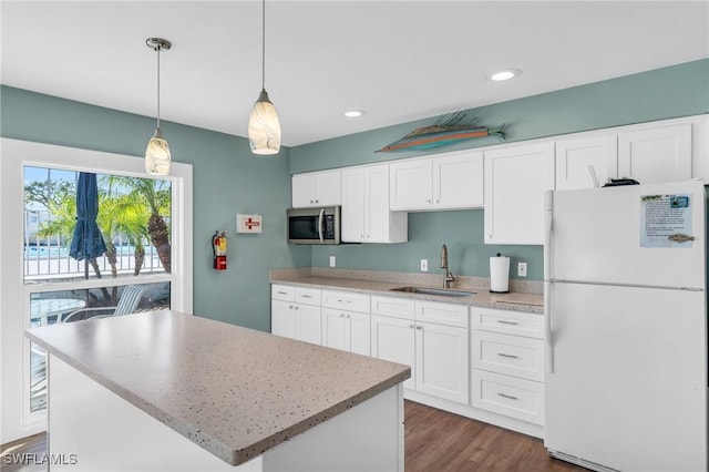 kitchen featuring white fridge, white cabinetry, sink, and hanging light fixtures